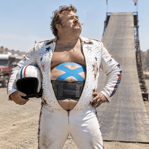 A daredevil with a taped belly and back brace stands beside a ramp.